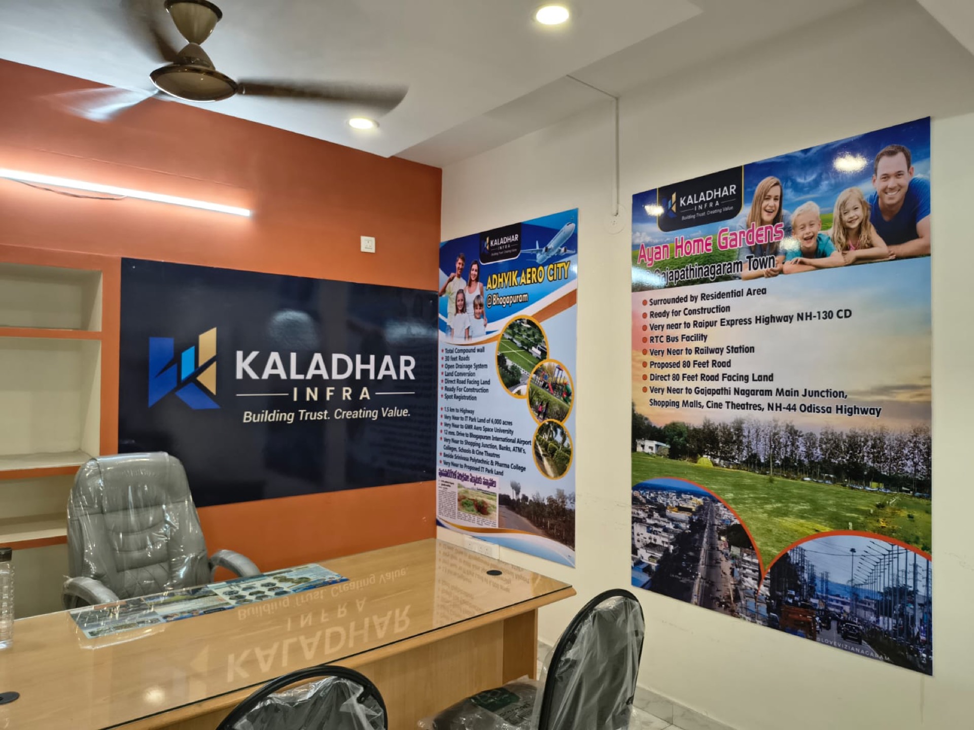 Inside the Kaladhar Infra office in Dwarakanagar, Visakhapatnam, with the brand wall and the Adhvik Aero City and Ayan Home Gardens project boards