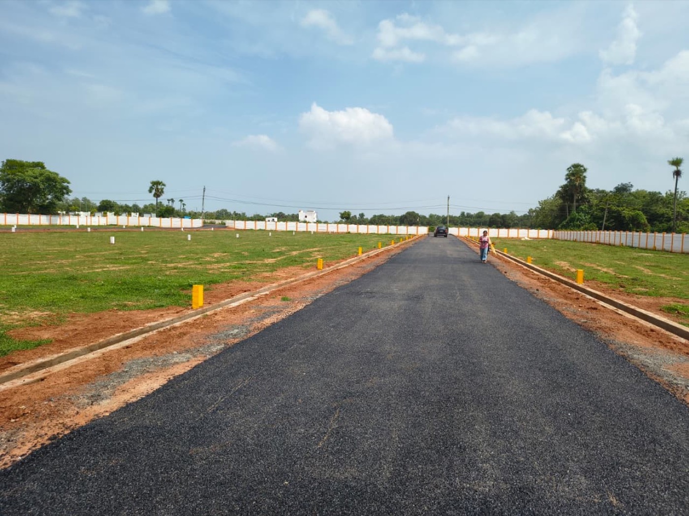 Blacktop internal road running straight through a developed Kaladhar Infra layout, plots marked on both sides