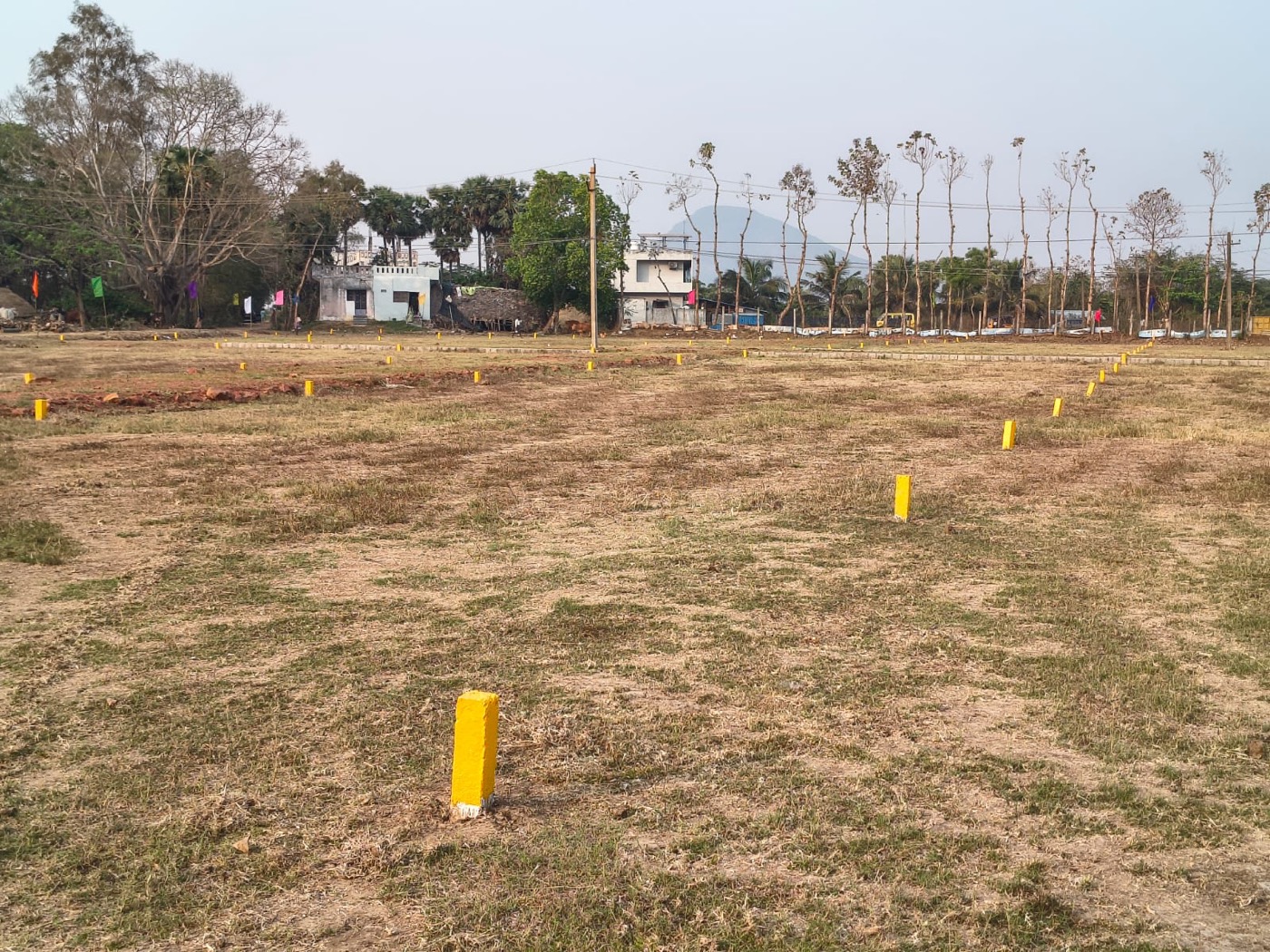 Demarcated residential plots with yellow boundary markers and the hills behind