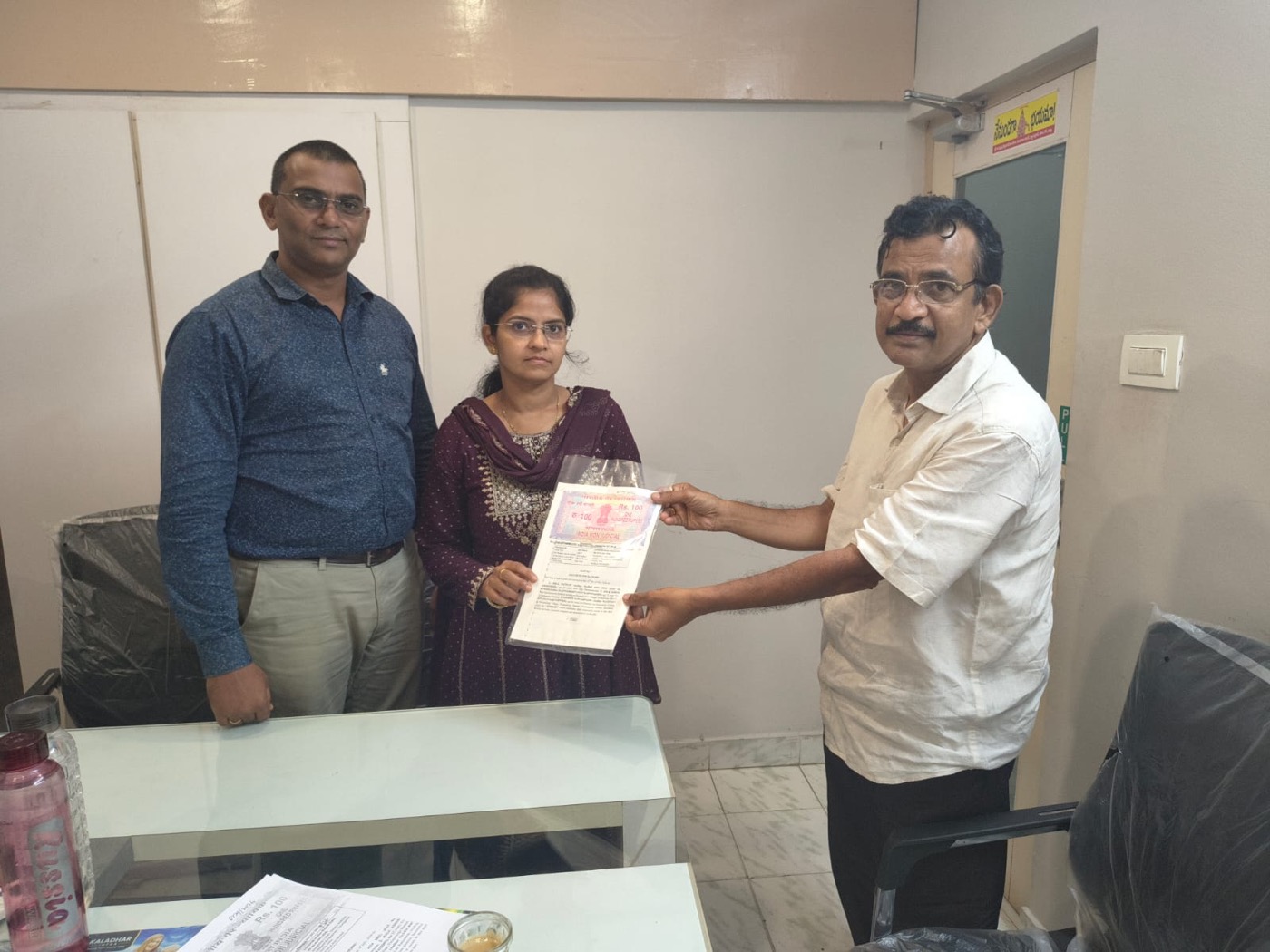 A couple receiving their plot agreement document from the Kaladhar Infra team at the office